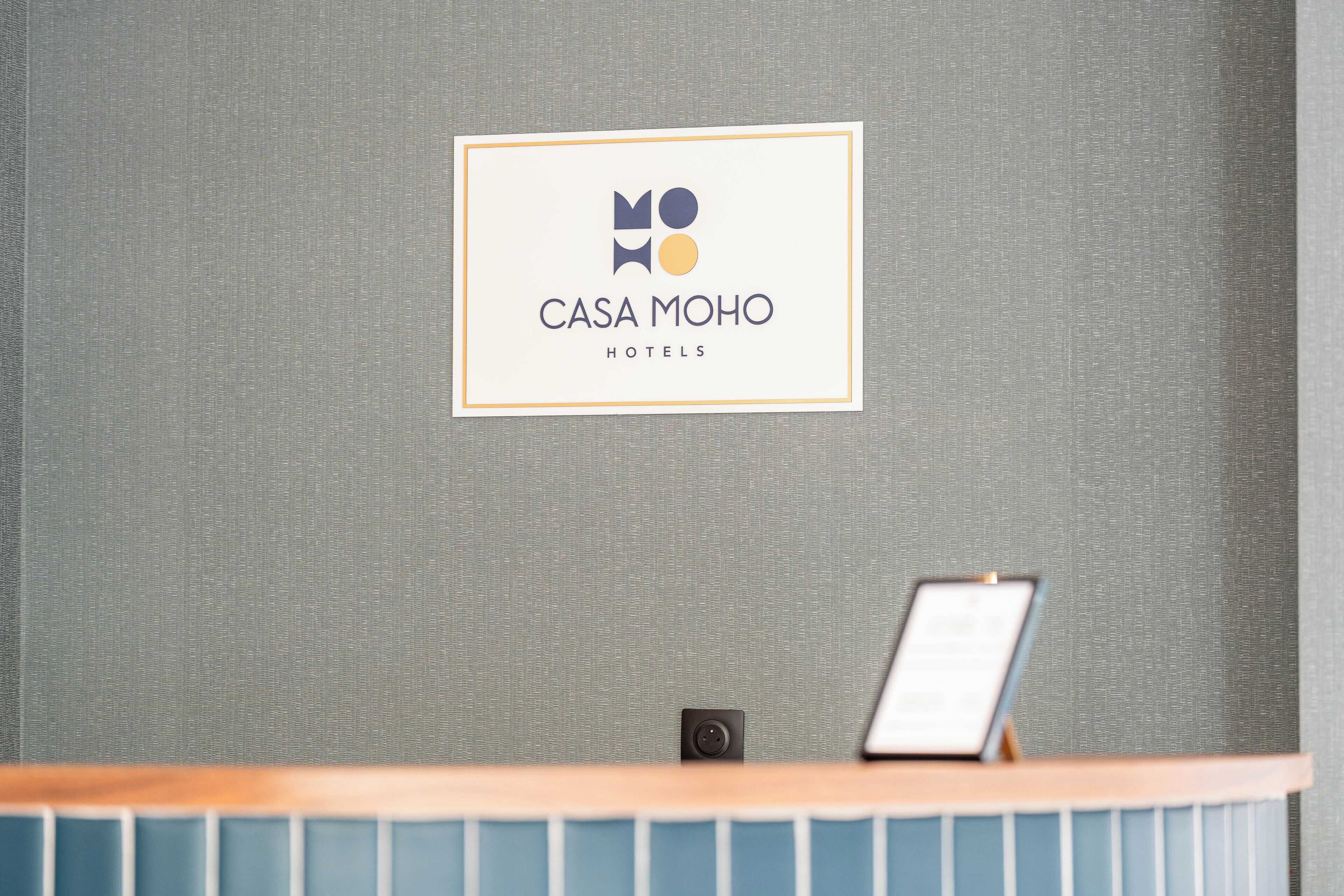 Una mesa de recepción con un cartel que dice 'CASA MOHO HOTELS' en la parte superior.