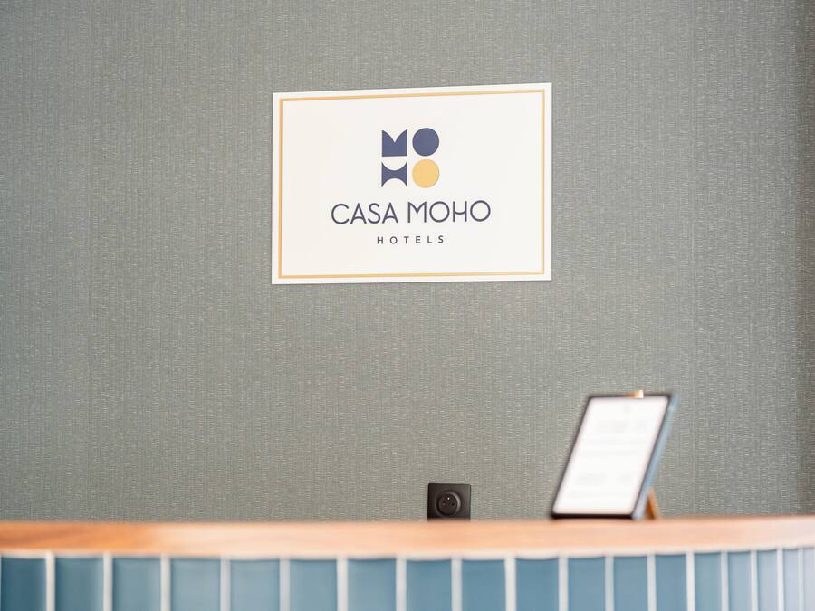 A reception desk with a sign for 'CASA MOHO HOTELS' above it.
