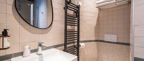 A bathroom with a white sink, a black towel rack, a toilet, and a mirror.