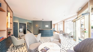 A hotel lobby with a reception desk, seating area, and a check-in counter. - CASA MOHO - Juan-Les-Pins (Antibes)