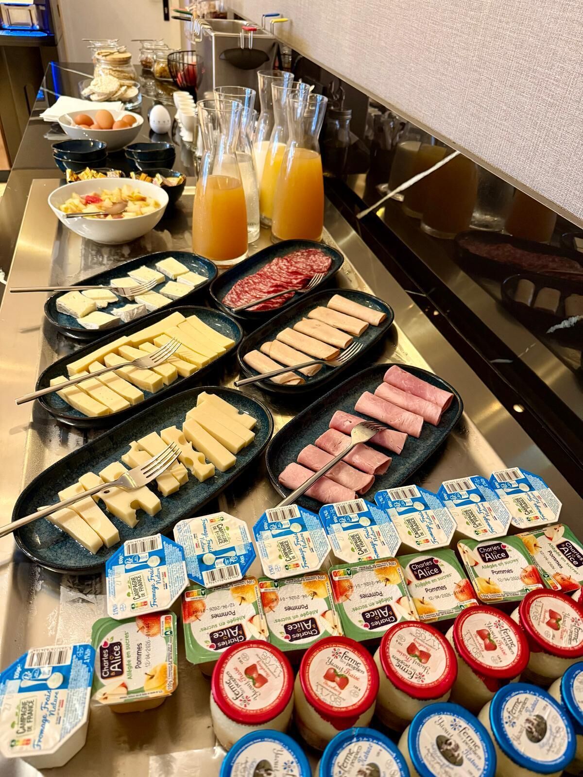 Un buffet proposant une variété d’aliments, notamment du fromage, du jambon et du yaourt.