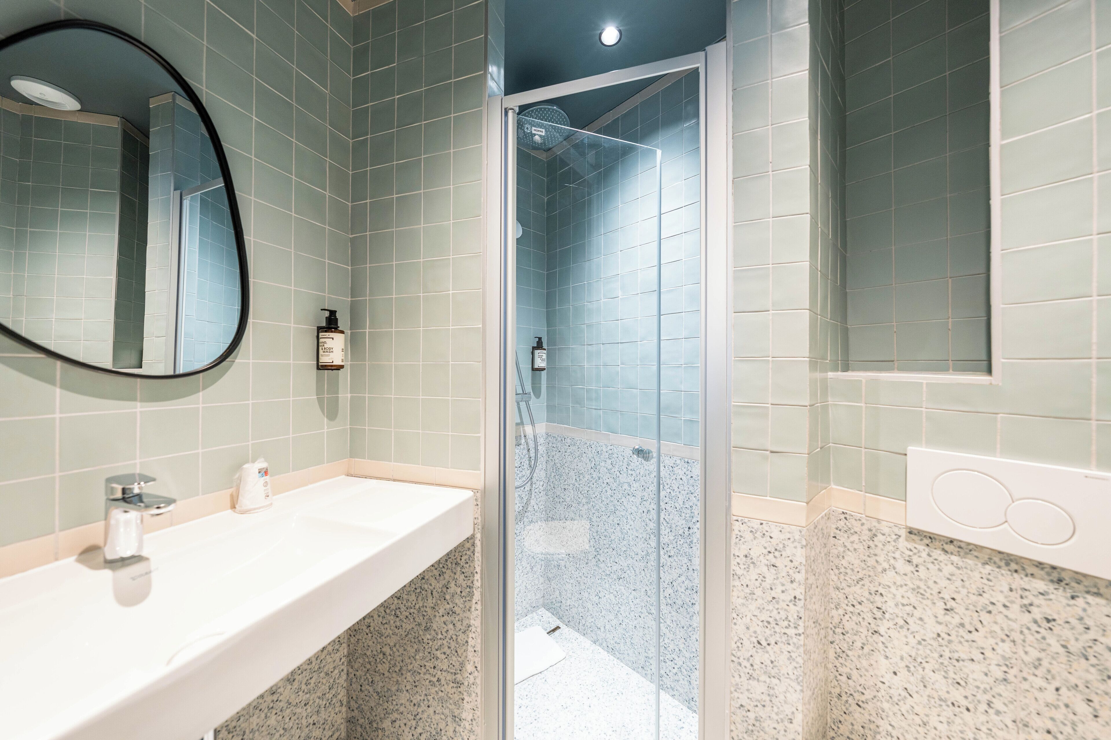 A bathroom with a sink, mirror, and shower.