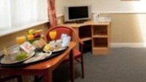 A room with a dining table set for two, a television on a stand, and a framed picture on the wall. - Moreton Park Lodge (Wrexham)