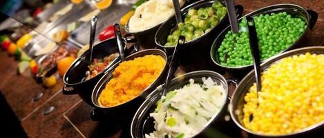 A buffet with various dishes including rice, peas, corn, and mashed potatoes.
