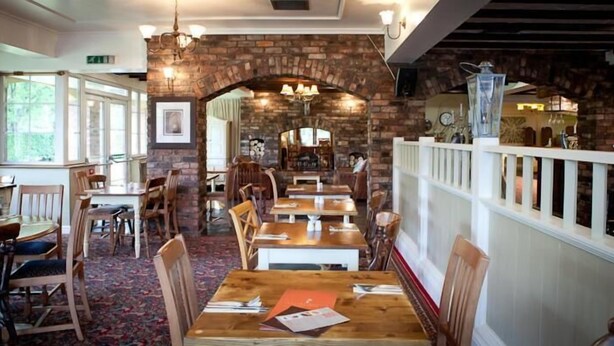A restaurant with brick walls, wooden tables, and chairs. - Moreton Park Lodge (Wrexham)