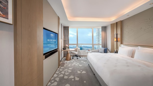 Une chambre d’hôtel avec un grand lit, un bureau, une chaise, une télévision et une vue sur la ville.