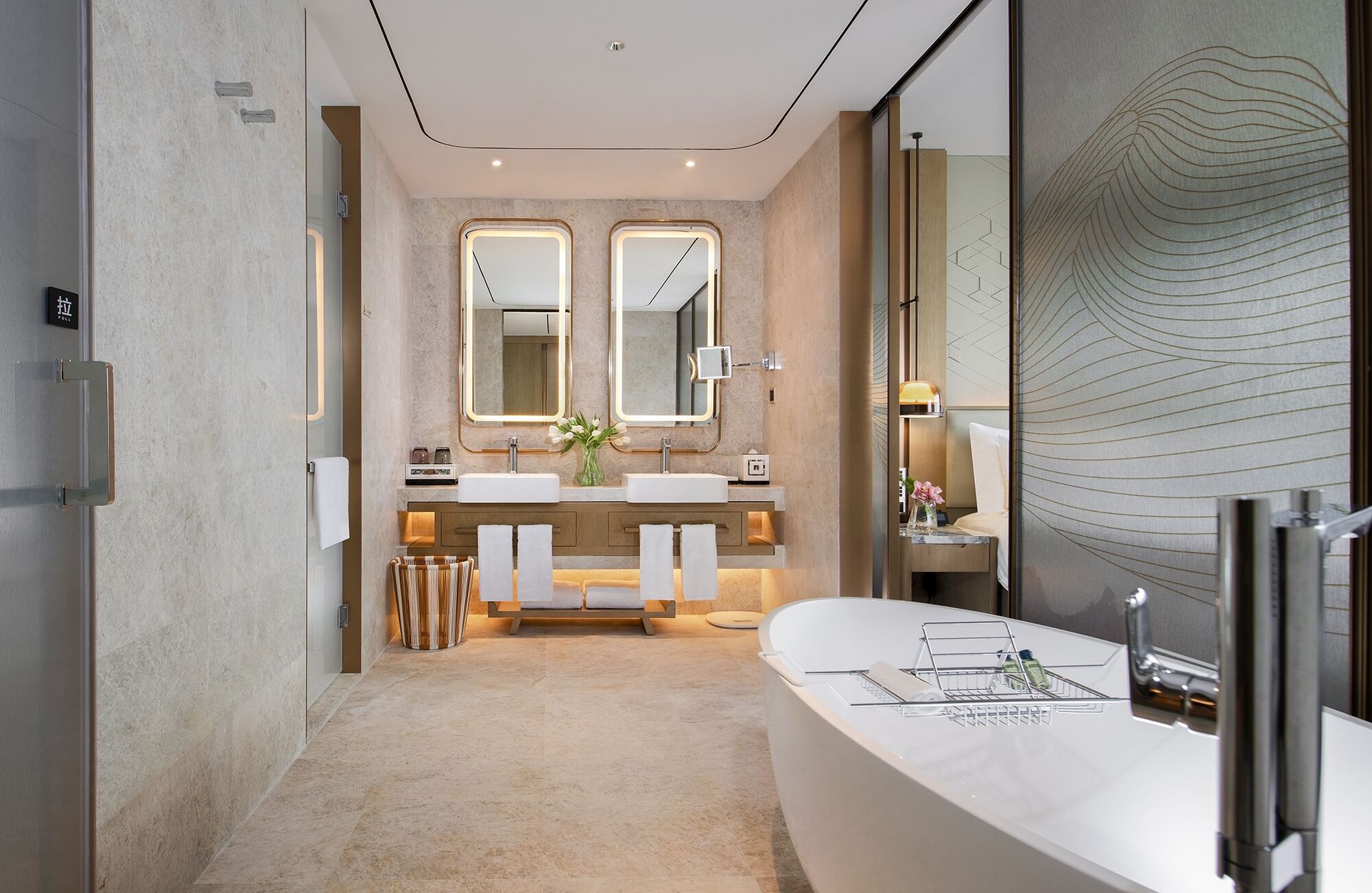 A modern bathroom with a large bathtub, two sinks, and a vanity with a mirror.