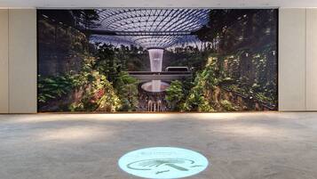 A spacious lobby with a large digital display featuring a tropical garden and a waterfall.