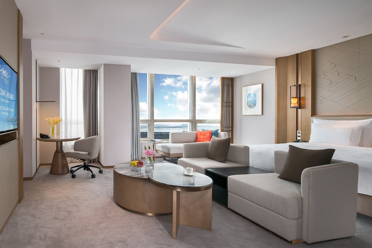 Une chambre d’hôtel moderne dotée d’un grand lit, d’un canapé, d’un bureau et offrant une vue sur la ville.