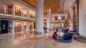 Un hall d’entrée spacieux, doté de hauts plafonds, de grandes colonnes et d’un espace salon central aménagé avec des meubles modernes.
