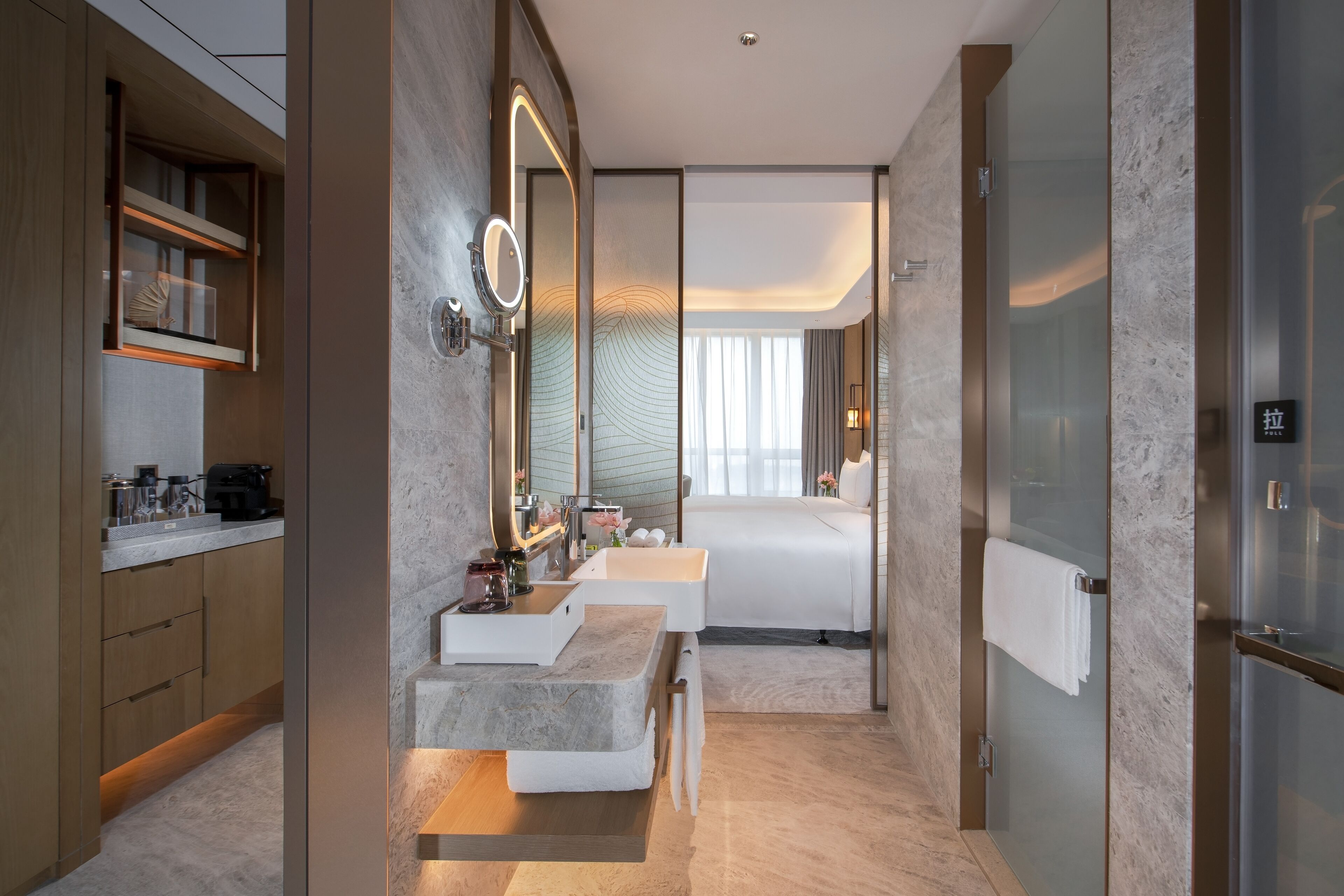 A modern hotel bathroom with a double sink vanity, a large mirror, and a glass shower enclosure.