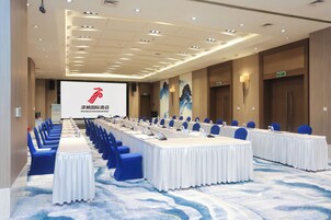 A conference room with a long table, blue chairs, and a presentation screen.