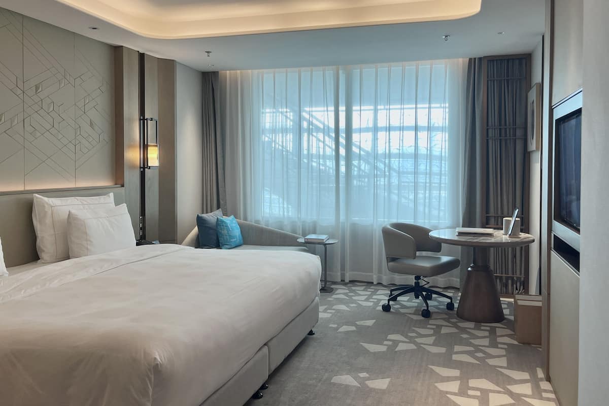 Une chambre d’hôtel moderne équipée d’un grand lit, d’un bureau, d’une chaise et d’une télévision.