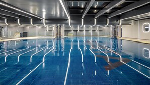 Un intérieur spacieux et moderne, agrémenté d’une grande piscine bleue aux reflets chatoyants et d’éléments de design élégants aux finitions métalliques.