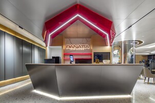 A modern reception desk with a geometric design, a digital screen, and a logo for Panatta Fitness.