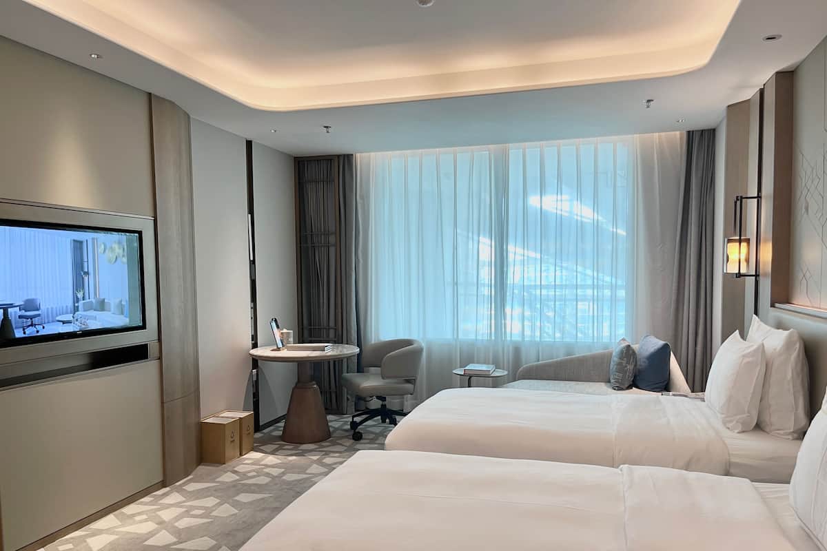 Une chambre d’hôtel avec deux lits, une télévision, une petite table et une chaise.