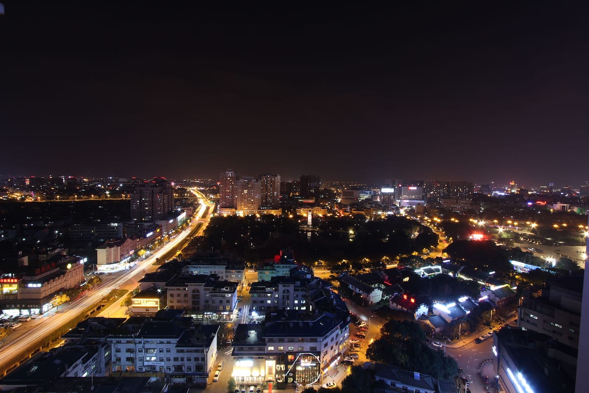 A nighttime cityscape with illuminated buildings and a busy road.
