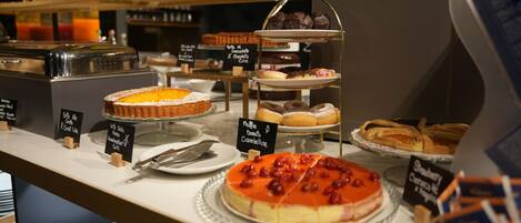 A bakery display with various cakes and pastries, including a cherry-topped cake and a chocolate cake.