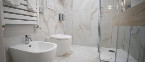 Ein modernes Badezimmer mit einem großen, weißen Waschbecken, einer Toilette und einer behindertzugänglichen Duschkabine.