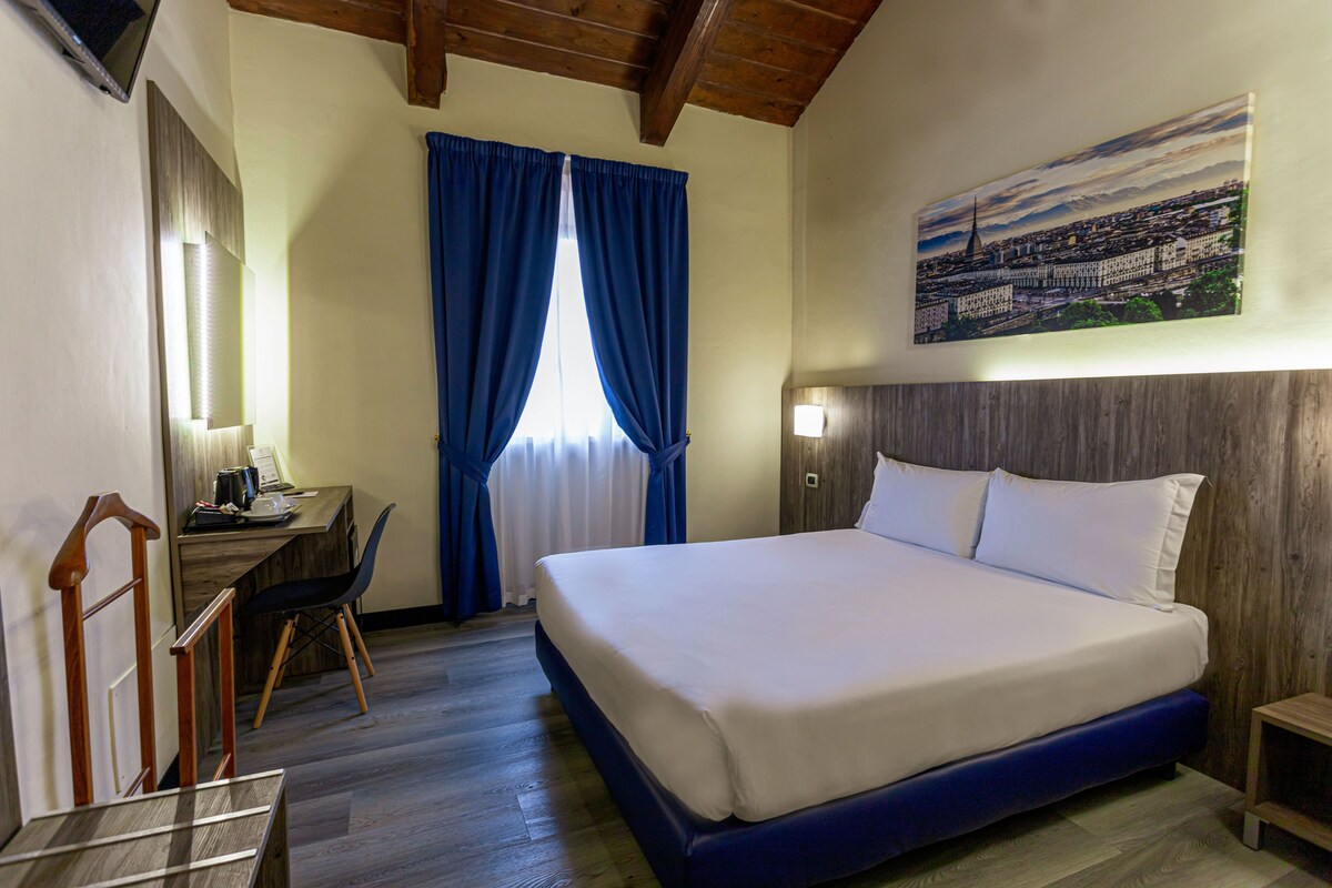 Une chambre d’hôtel avec un lit, un bureau, une chaise et un tableau au mur.