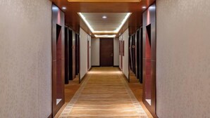 A hotel hallway with a wooden floor, recessed lighting, and multiple doors on either side.