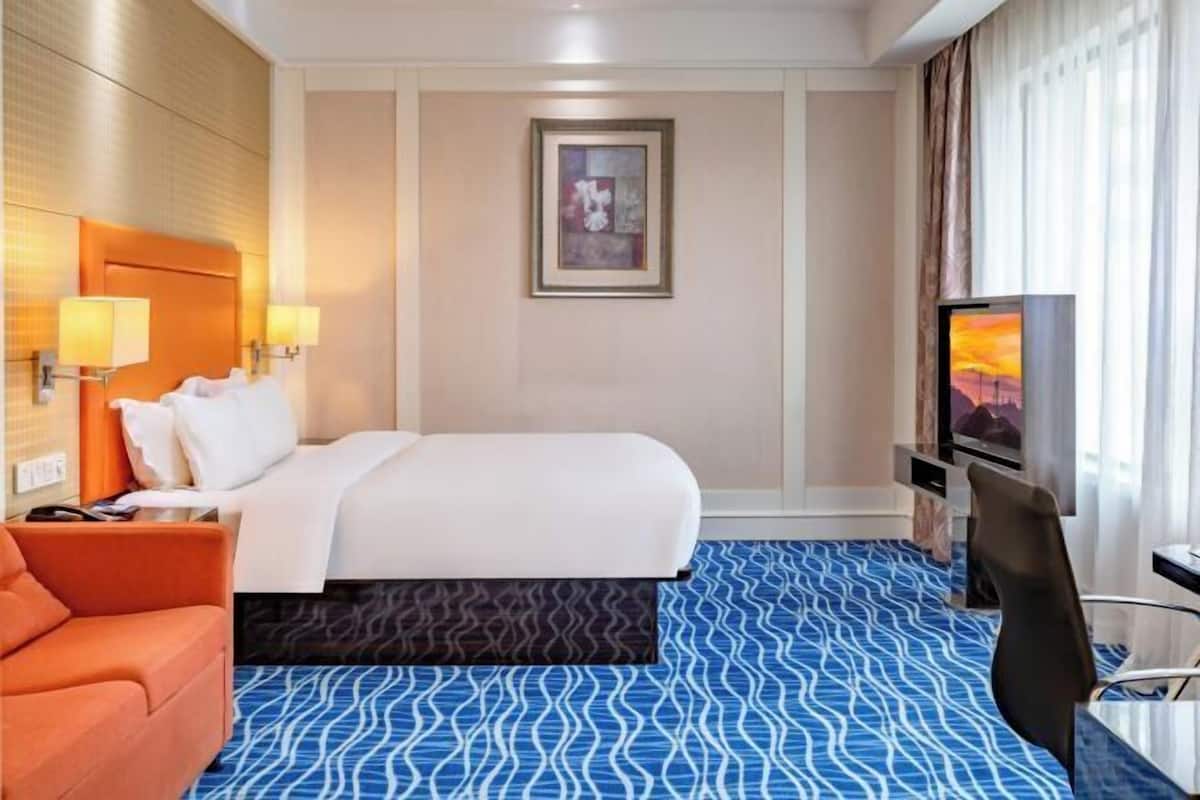 A hotel room with a bed, a TV, a desk, and a chair.