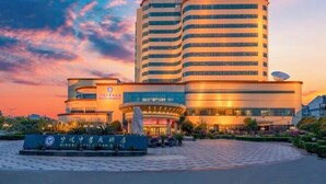A modern hotel with a curved facade, a prominent entrance, and a landscaped area in front. - Ningbo Zoyi Grand Hotel (Ningbo)