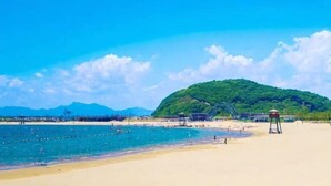 A beach with a lifeguard tower, clear blue sky, and a hill in the background. - Ningbo Zoyi Grand Hotel (Ningbo)