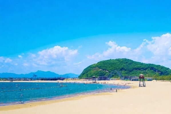 A beach with a lifeguard tower, clear blue sky, and a hill in the background. - Ningbo Zoyi Grand Hotel (Ningbo)