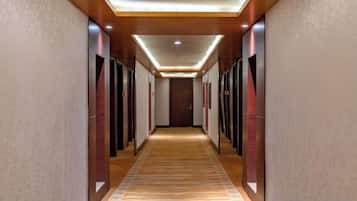 Pasillo de hotel con piso alfombrado, puertas a ambos lados y techo con iluminación empotrada.