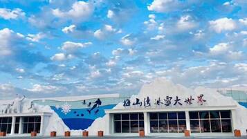 Un edificio con un mural grande de una copo de nieve y caracteres chinos, un estacionamiento y un cielo despejado.