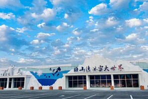 Um edifício com um grande mural de floco de neve e caracteres chineses, um estacionamento e céu claro.