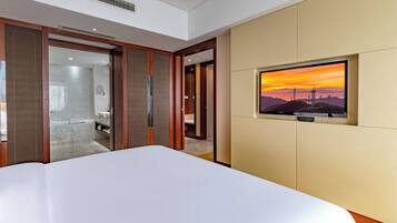 Habitación de hotel con una cama grande, un televisor montado en la pared y una puerta corredera que da al baño.