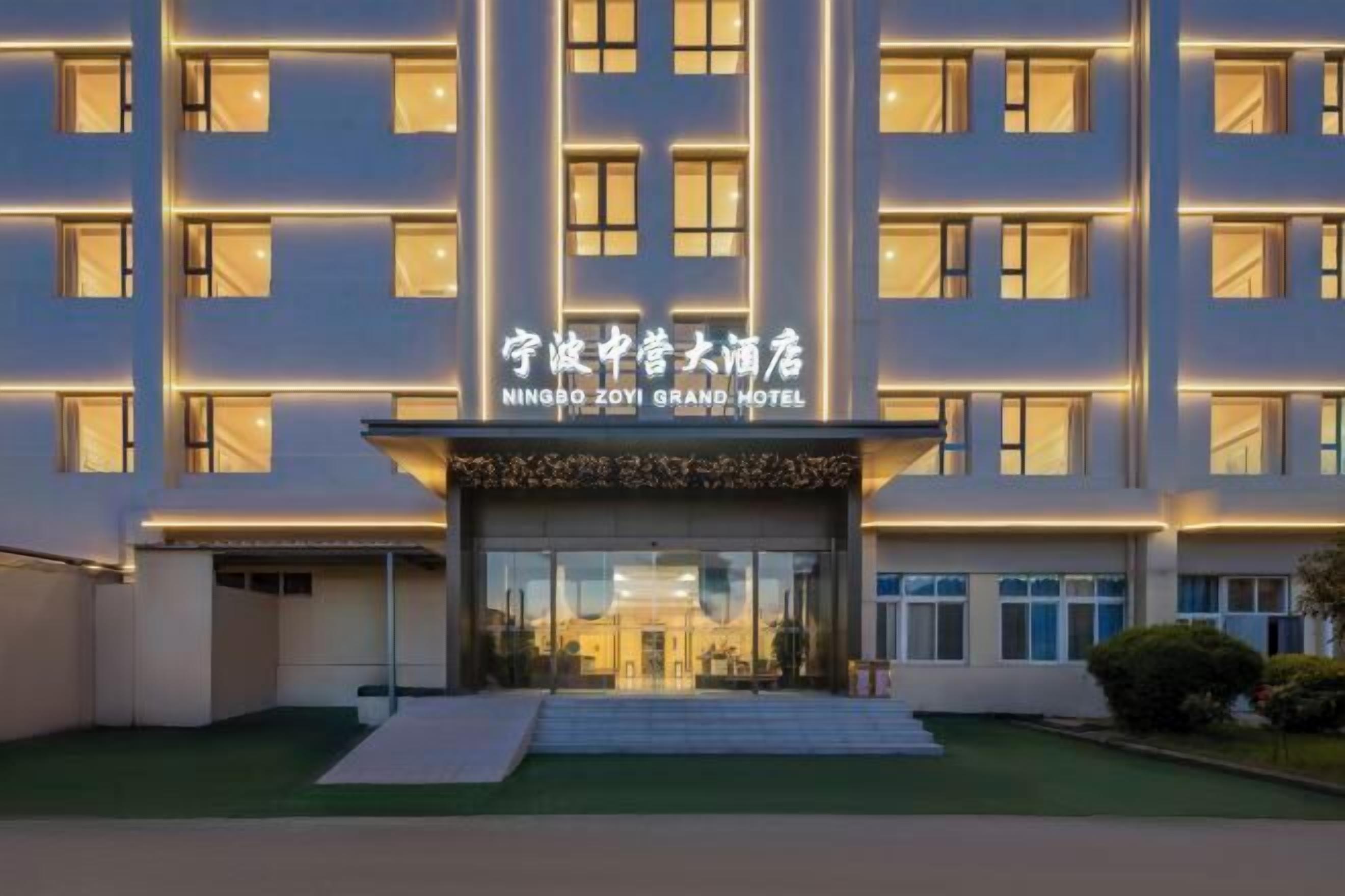 A multi-story hotel with a modern facade, illuminated signage, and a well-maintained entrance area.