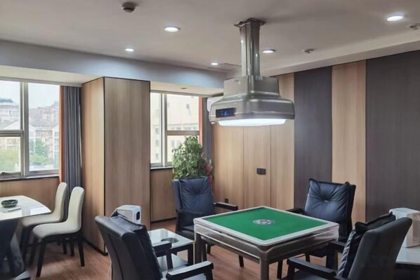 Une pièce avec une table de billard, des chaises, une table avec un ordinateur et une grande fenêtre.
