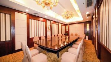 A conference room with a long table and chairs, a chandelier, and patterned carpet.