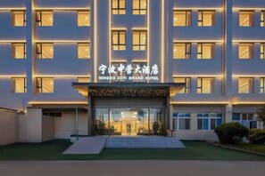 Un hotel de varios pisos con una entrada destacada y señalización en chino e inglés.