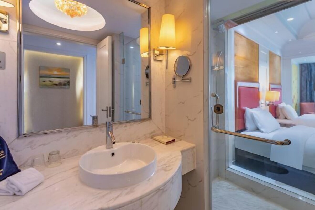 Un baño moderno con un lavabo redondo, un espejo grande y una cabina de ducha con paredes de cristal.