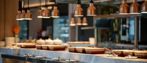 Cozinha moderna com iluminação pendente, bancada de mármore e diversos utensílios de cozinha.