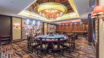 A hotel conference room with a round table, chairs, and a chandelier.