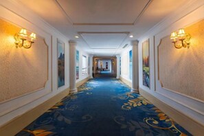 Un pasillo de hotel con alfombra estampada, iluminación empotrada en la pared y cuadros enmarcados.