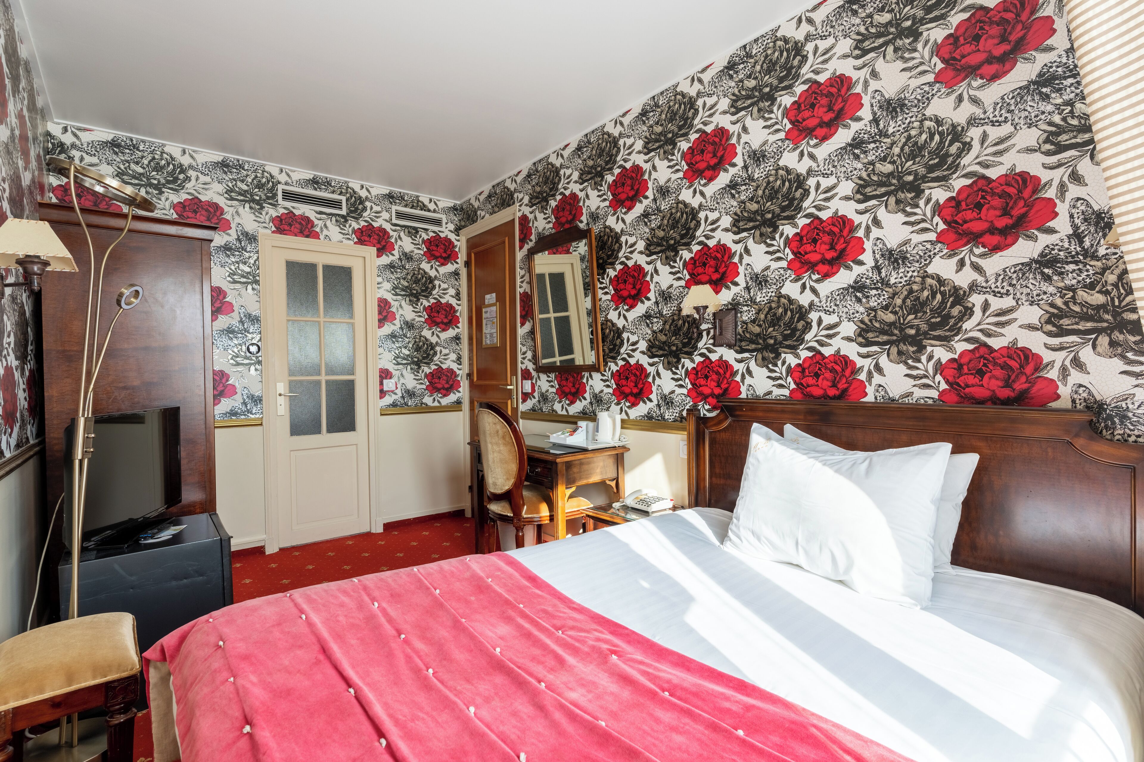 Ein Schlafzimmer mit Bett, Schreibtisch, Stuhl, Fernseher und Kleiderschrank.
