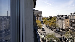 A view from a window overlooking a street with the Arc de Triomphe and the Eiffel Tower in the background.