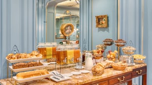 A breakfast buffet with various pastries, fruits, and beverages.