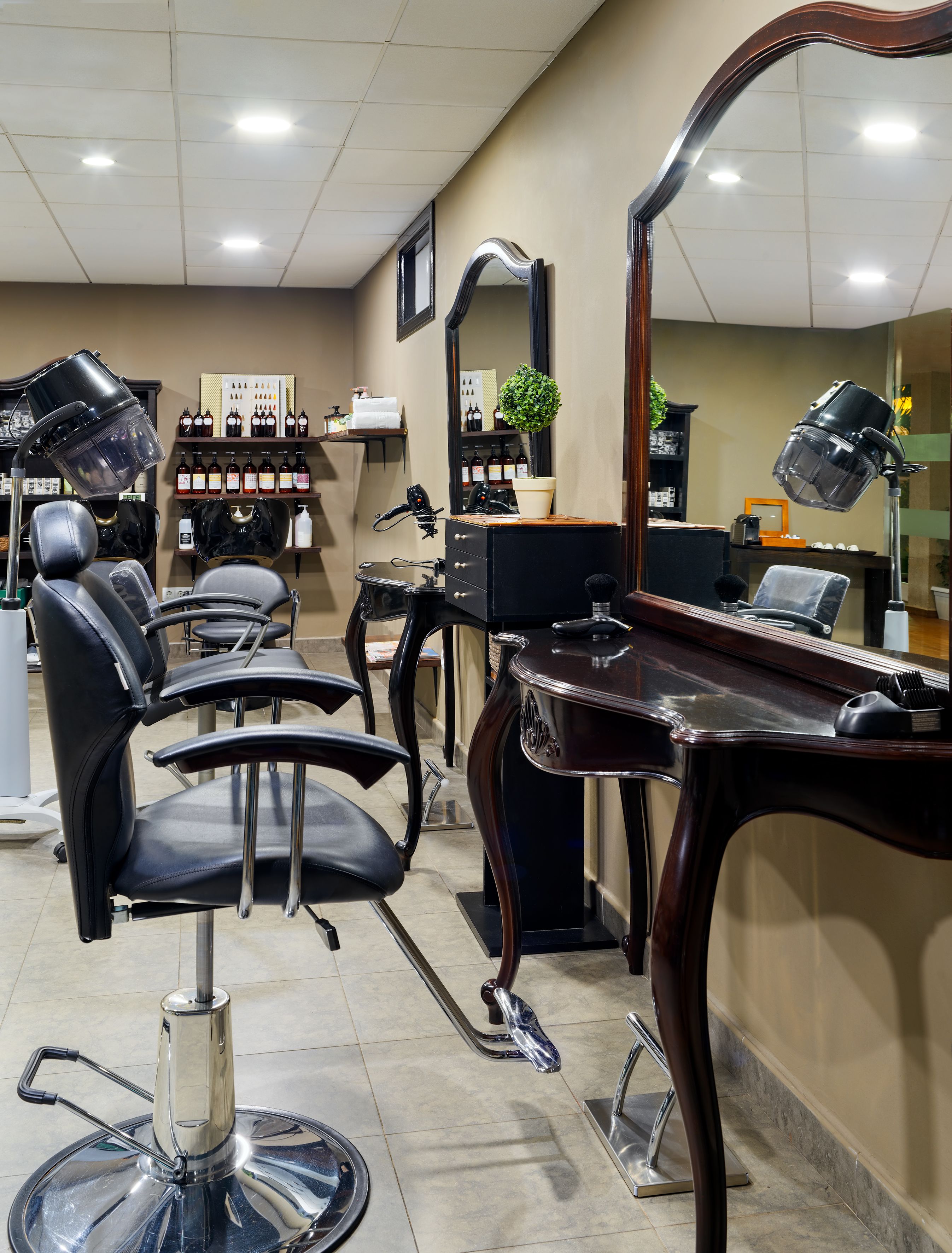 Ein Friseursalon mit mehreren schwarzen Friseurstühlen, einem großen Spiegel und verschiedenen Haartool-Accessoires auf der Theke.