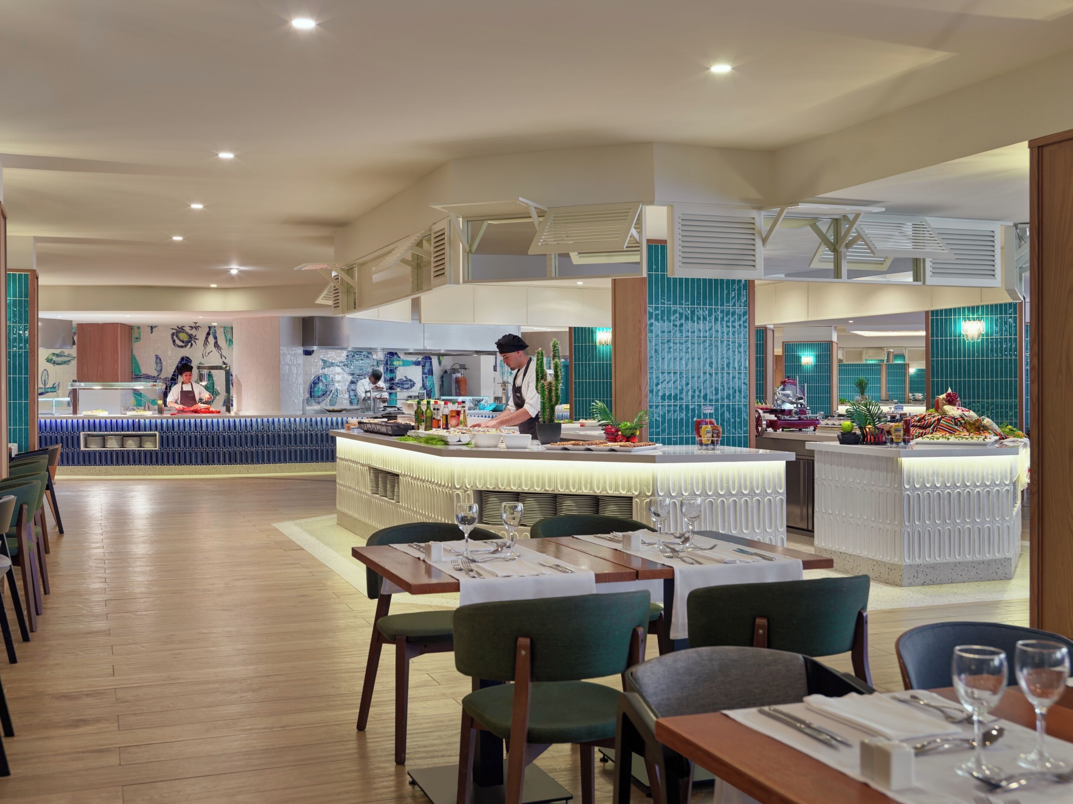 Un restaurante moderno con una barra central, varias zonas de estar y un chef preparando comida.