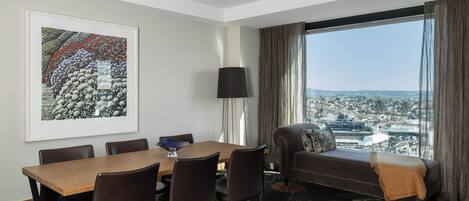 Et moderne hotelværelse med spiseplads, sofa med udsigt og et stort vindue.