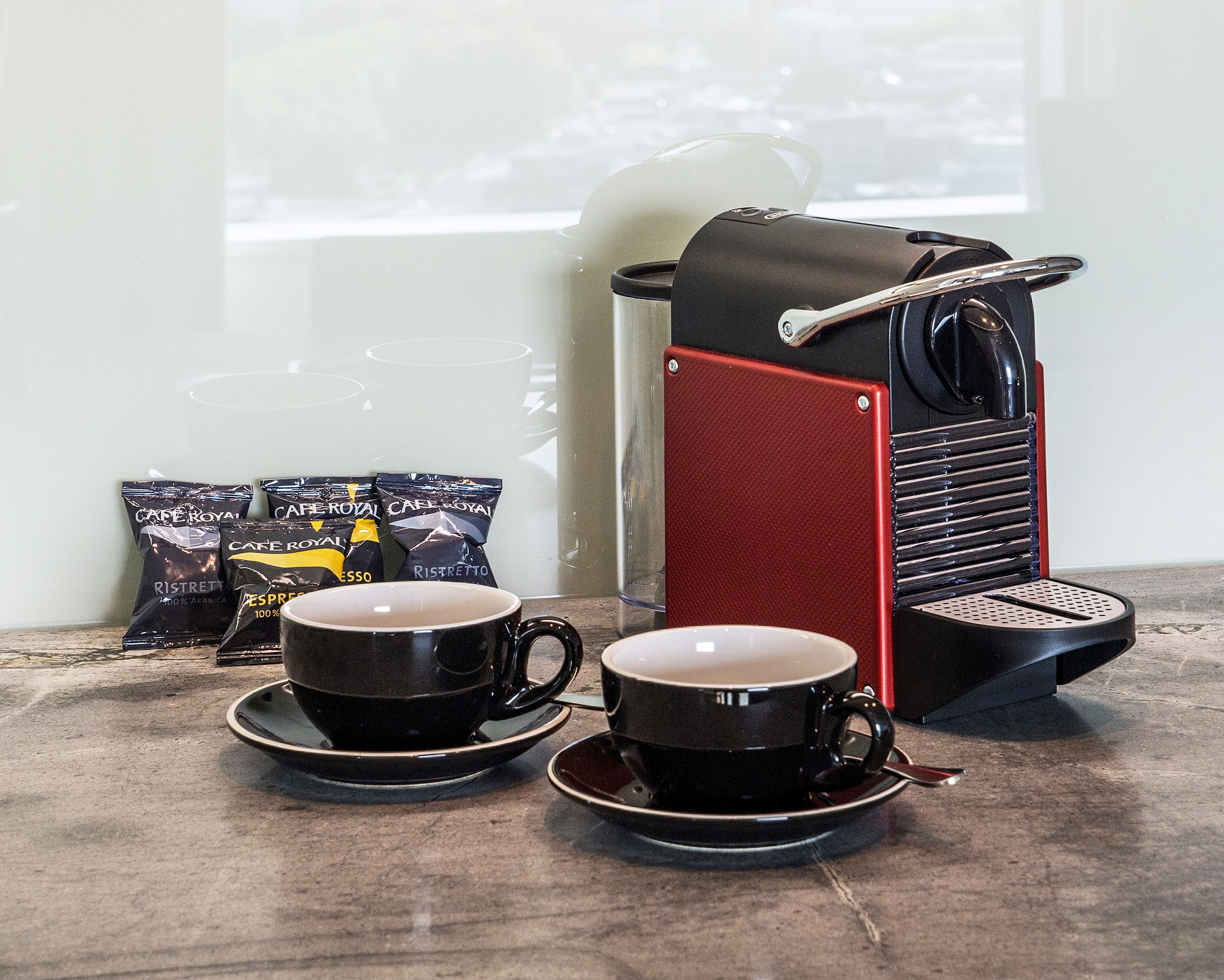 A coffee machine with two cups of coffee on a table.