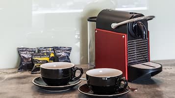 A coffee machine with two cups of coffee on a table.