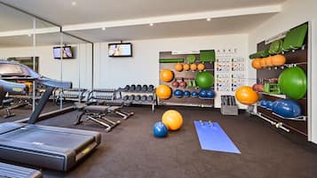 A gym with treadmills, dumbbells, and exercise balls.